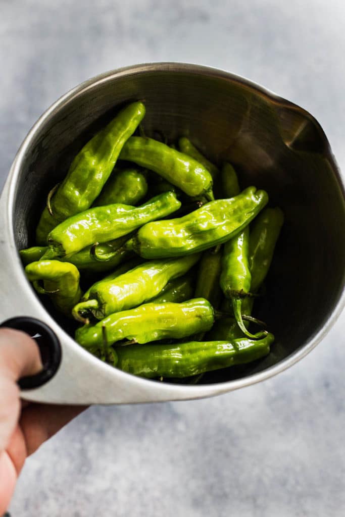 Mildly spicy blistered shishito peppers tossed with olive oil, lemon and salt are paired with a fresh citrus pesto dip for the perfect finger food appetizer.